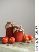 Homemade tomato juice in glass jars with fresh tomatoes, garlic, and spices. Rustic, cozy shot for recipes, healthy food blogs and agricultural concepts. Стоковое фото, фотограф Елена Никишина / Фотобанк Лори