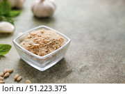 Nutritional yeast flakes in glass bowl with ingredients like garlic, basil and pine nuts on speckled background with copy space. Ingredients for lactose free pesto sauce. Стоковое фото, фотограф Елена Никишина / Фотобанк Лори