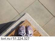 Sneakers stand on wooden planks against background of paving stones. Стоковое фото, фотограф Aleksandra Selivanova / Фотобанк Лори