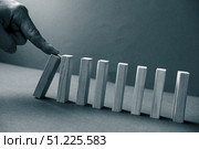 Domino has Fallen in a Row. Domino theory. Effect. Hand with Finger is Pointing and Pushing the Falling Wood Blocks. Risk Management, Revolution Concept. Affect Business. Closeup. Manifestation. Red. Стоковое фото, фотограф Марина Демидюк / Фотобанк Лори