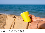 Paper disposable cup in hand on the beach. Close-up, selective focus. Стоковое фото, фотограф Никита Бурденков / Фотобанк Лори