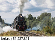 An old Soviet steam locomotive of the L series. The Ruskeala Express retro train is on its way to the mountain park. Thick smoke is coming from the chimney. Russia, Republic of Karelia, Sortavala, August 10, 2025. Редакционное фото, фотограф Photojuli / Фотобанк Лори