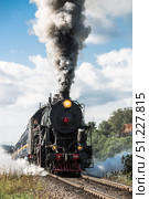 An old Soviet steam locomotive of the L series. The Ruskeala Express retro train is on its way to the mountain park. Thick smoke is coming from the chimney. Russia, Republic of Karelia, Sortavala, August 10, 2025. Редакционное фото, фотограф Photojuli / Фотобанк Лори
