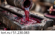 Rich red liquid pours from traditional vat during winemaking process in rural vineyard setting. Стоковое AI-изображение, AI-художник Александр Довянский / Фотобанк Лори