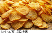 A Close-Up View of Crispy Ridged Potato Chips on a Wooden Surface. Generative AI. Стоковое AI-изображение, AI-художник Roman Zavorotny / Фотобанк Лори