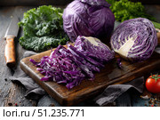 Organic freshly white cabbage on rustic table surface. Purple fresh cabbage. Partially sliced raw shredded cabbage and a half on a wooden cutting board with a knife. Preparation of vegetables salad. Стоковое AI-изображение, AI-художник Марина Демидюк / Фотобанк Лори