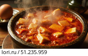 Steaming mapo tofu in stone bowl with egg on side. Стоковое фото, фотограф David Kashakhi / Фотобанк Лори
