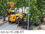 JCB construction telehandlers and wheel loaders parked on a street. London, UK, 14 July 2024. Редакционное фото, фотограф Zydrius Tartenis / Фотобанк Лори