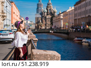 Church of the Resurrection of Christ (Spas-na-Krovi). A woman in a hat with a cigarette on the embankment in front of the church. Russia, St. Petersburg, August 15, 2025. Редакционное фото, фотограф Photojuli / Фотобанк Лори