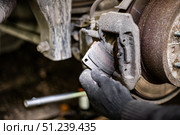 A gloved hand installs a new brake pad into a car caliper, ensuring smooth and safe operation. Стоковое фото, фотограф Коханова Наталья / Фотобанк Лори