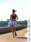 A woman runs on a sidewalk with a white jacket and a black tank top.  Russia. Moscow. 24.08.25. Редакционное фото, фотограф Ярославский Максим / Фотобанк Лори