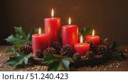 Red candles with pinecones and holly leaves for holiday decoration. Стоковое AI-видео, аниматор KATERINA AI / Фотобанк Лори