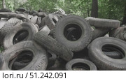 In a dense forest, piles of discarded rubber tires lie abandoned, highlighting the severe problem of pollution and its harmful effects on the surrounding ecosystem and wildlife. Стоковое видео, видеограф Громов Александр / Фотобанк Лори
