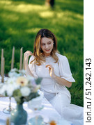 A woman in a white dress sits at a table in a serene setting. Стоковое фото, фотограф Cantemir Dumitru / Фотобанк Лори
