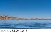 Beautiful blue lake. Reed houses are visible on the shore, boats Balsa de totora are moored, tourist ships. Clear sky. Copy space. Peru. Uros Floating Islands. Lake Titicaca. Стоковое фото, фотограф Вера Ивановна Кубарева / Фотобанк Лори