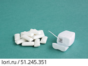 Dental floss in white container and heap of chewing gums on blue background, copy space for text. Стоковое фото, фотограф Зарифа Арсланова / Фотобанк Лори