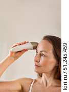 Middle-aged Woman Uses Skincare Device Indoors to Revive Youthful Skin Appearance. Стоковое фото, фотограф Aleksandr Golubev / Фотобанк Лори