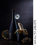 Contemporary still life with banana, dandelion in a bottle and sunflowers on a dark background. Стоковое фото, фотограф Ирина Толокновская / Фотобанк Лори