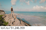 Woman posing on cliff edge in Tulum overlooking the Caribbean Sea in Mexico. Стоковое видео, видеограф Ольга Сухарева / Фотобанк Лори
