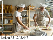 Two bakers prepare doughs for baking delicious bread - giving it the shape of baguette. Стоковое фото, фотограф Татьяна Яцевич / Фотобанк Лори