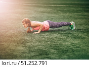 Fit woman in bright sports clothes to do burpees on the green grass. Стоковое фото, фотограф Арзюков Вадим Николаевич / Фотобанк Лори