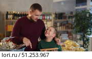 Man with a child in a supermarket is choosing groceries. Single father and his son are shopping at a grocery store. Стоковое видео, видеограф Яков Филимонов / Фотобанк Лори