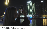 A woman photographs a vibrant city skyline at night, capturing its beauty. Стоковое видео, видеограф Cantemir Dumitru / Фотобанк Лори