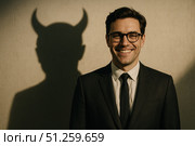 Confident Man in Suit with Playful Devil Shadow; A Visual Representation of Duality, Charm, and the Intriguing Nature of Human Personality. Стоковое AI-изображение, AI-художник Башкирова Анна / Фотобанк Лори