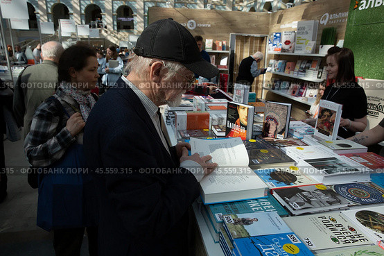 06.04.2023, Москва. Международная ярмарка интеллектуальной литературы «non/fictioNвесна» в Гостином дворе. Мужчина рассматривает книгу на прилавке. Редакционное фото, фотограф Дмитрий Киселёв / Фотобанк Лори