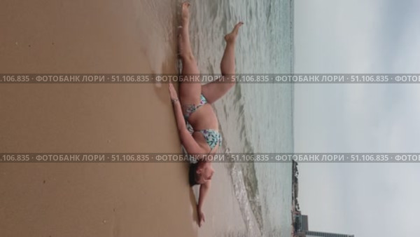 A 50-year-old European woman in a swimsuit walks along the beach in Doha, Qatar. Стоковое видео, видеограф IRYNA ZAKHARANKA / Фотобанк Лори
