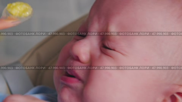 A baby experiences a surprising reaction to solid food for the first time during mealtime at home. The adorable expression shows curiosity mixed with uncertainty. Стоковое видео, видеограф Воловодов Владимир / Фотобанк Лори