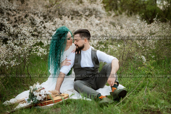 a bearded groom plays a stringed instrument and a girl with green hair sits in a spring meadow. Стоковое фото, агентство Ingram Publishing / Фотобанк Лори