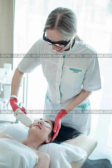 A beautician makes a diode laser rejuvenation procedure. Стоковое фото, фотограф София Тюленева / Фотобанк Лори