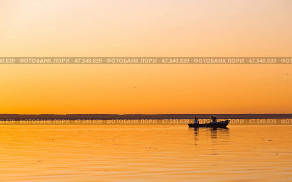 A beautiful fiery sunset and a boat on Pleshcheyev lake in Pereslavl Zalessky. Beautiful sunset and water surface. Стоковое фото, фотограф Photojuli / Фотобанк Лори