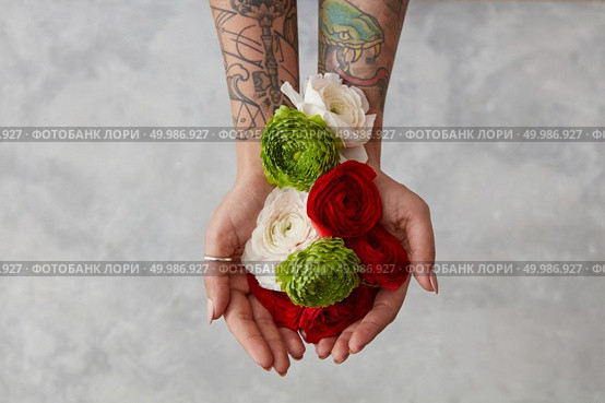 a bouquet of fresh flowers, a girl with a tattoo on her hands holding flowers on a gray background. The concept of a greeting card top view. girl with a tattoo on her hands holding a bouquet of flowers. Стоковое фото, агентство Ingram Publishing / Фотобанк Лори