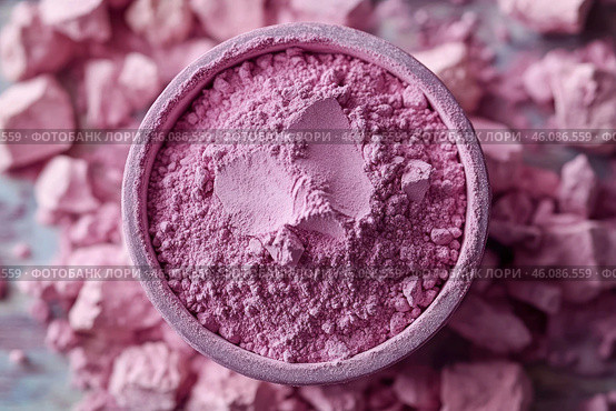 A bowl filled with pink powder, with lumps and particles of the substance scattered around. The texture of the powder looks loose and airy, with small lumps that create a feeling of natural and soft material. The color is rich, pink, which makes the scene visually pleasing and delicate. The background is blurred, but supports the main color palette, creating a harmonious image. Стоковое AI-изображение, AI-художник Анна Кривицкая / Фотобанк Лори