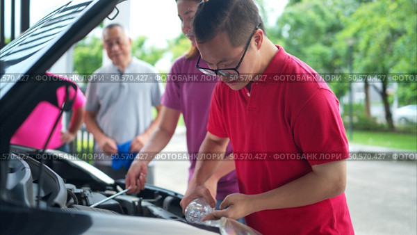 A brother and sister help each other execute a basic engine check on their parents’ automobile. Стоковое фото, агентство Ingram Publishing / Фотобанк Лори