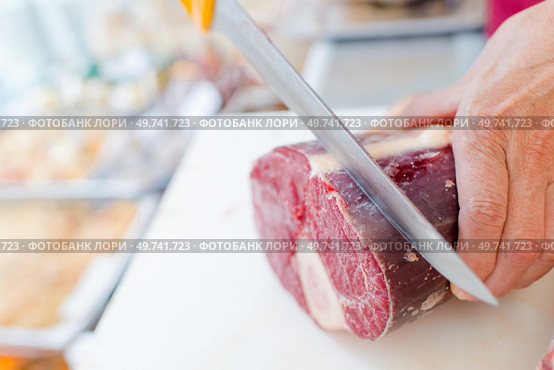 a butcher is slicing beef. Стоковое фото, агентство Ingram Publishing / Фотобанк Лори