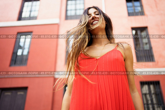 A cheerful woman in a vibrant red dress enjoys a sunny day in an urban setting, radiating happiness and confidence as she joyfully explores her surroundings with enthusiasm, embracing the moment. A Joyful Woman in a Beautiful Red Dress Posing Against a Lively Urban Backdrop Scene. Стоковое фото, агентство Ingram Publishing / Фотобанк Лори