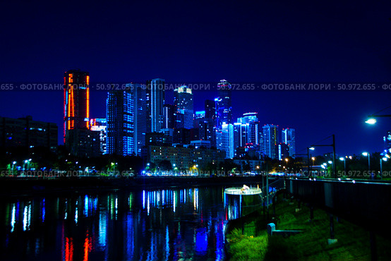 A city skyline is lit up at night with the lights reflecting on the water. Residential complex on Shelepikhinskaya embankment. Russia. Moscow. 03.08.2025. Редакционное фото, фотограф Ярославский Максим / Фотобанк Лори