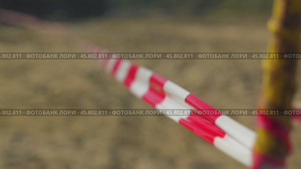 A close-up of a red and white striped tape, commonly used for cordoning off areas. The tape stretches into the distance, creating a sense of perspective. The background is blurred. Стоковое видео, видеограф Воловодов Владимир / Фотобанк Лори