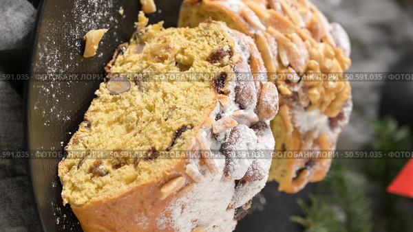 A close-up of a slice of Bolo Rainha, a traditional Portuguese sweet bread, sprinkled with powdered sugar and adorned with almonds and walnuts. Стоковое фото, агентство Ingram Publishing / Фотобанк Лори