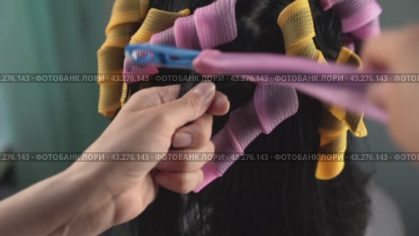 A close-up shot of a hairdresser applying perm solution to a clients hair. Стоковое видео, видеограф Андрей Знаменский / Фотобанк Лори