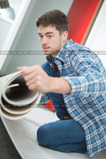 a contractor is unrolling underlay. Стоковое фото, агентство Ingram Publishing / Фотобанк Лори