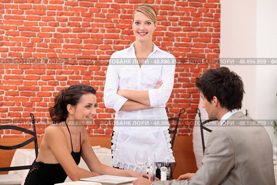 a couple dining at a restaurant and a waitress crossing her arms. Стоковое фото, агентство Ingram Publishing / Фотобанк Лори