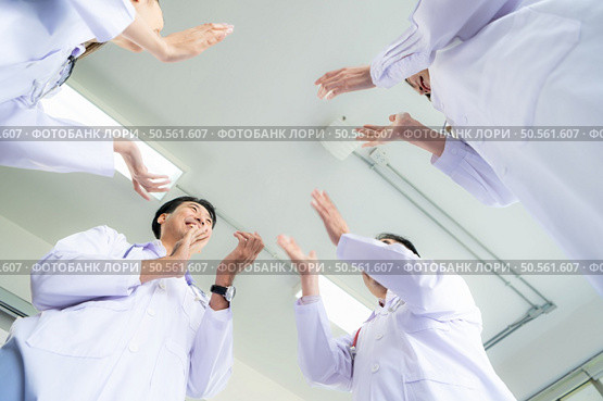 A delighted doctor team enjoying achievement in a hospital setting with clap hands. Стоковое фото, агентство Ingram Publishing / Фотобанк Лори