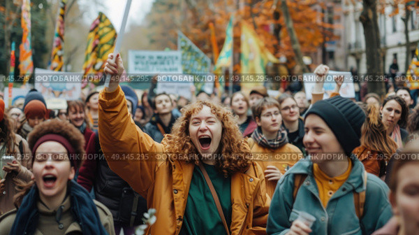 A diverse group of enthusiastic protesters march through a street lined with autumn trees, holding signs and banners while chanting and raising their fists. Стоковое AI-изображение, AI-художник Данила Большаков / Фотобанк Лори