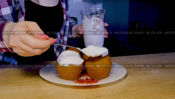 A girl in a plaid shirt is frosting several small cupcakes in the kitchen. Стоковое видео, видеограф Катерина Белякина / Фотобанк Лори