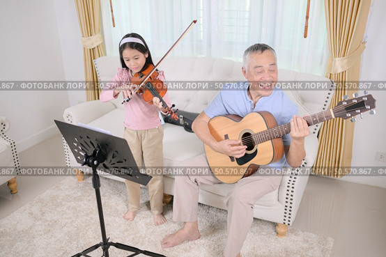 A girl violinist and her grandfather practice music together at home. Стоковое фото, агентство Ingram Publishing / Фотобанк Лори