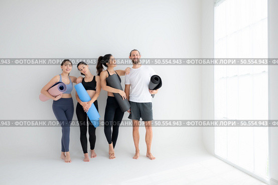 A group of female and male athletes stood and chatted amicably in the studio before beginning with the yoga class. Стоковое фото, агентство Ingram Publishing / Фотобанк Лори